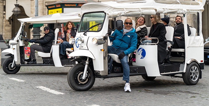 Group of travellers aboard a white Pegaso electric tuk tuk in Rome